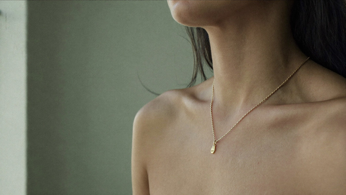 Gouden ketting met kleine hanger op de hals